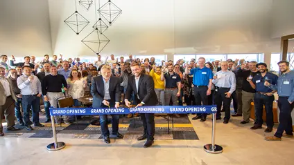 Grand opening of a building. Two men cutting a ribbon, with lots of people standing behind them