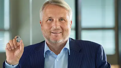Man in a suit holding a small metal part