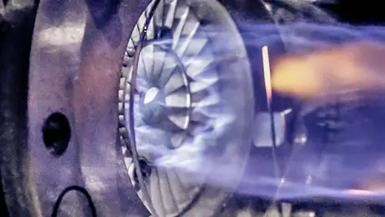 Round machinery creating a large blue flame
